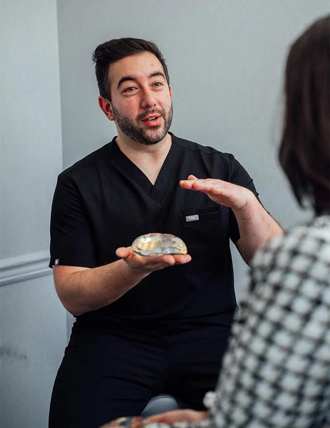 Healthcare professional in black scrubs explaining dental procedure while holding dental model to patient - breast revision in Parsippany, NJ.