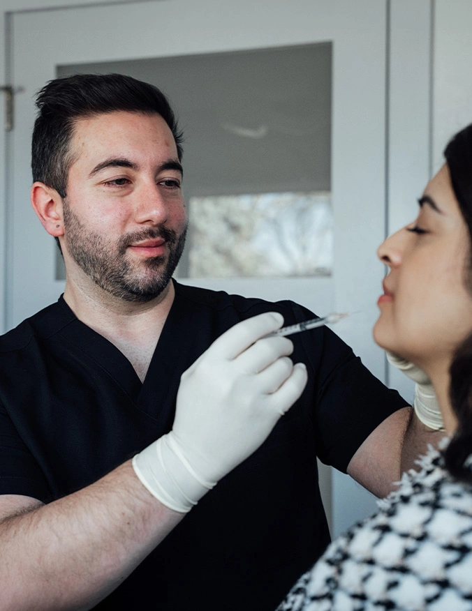 Medical professional in black scrubs examining female patient's face during cosmetic consultation - Dermal fillers in Parsippany, NJ.