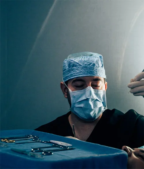 Surgeon Shuja in surgical mask and cap performing operation in sterile operating room environment