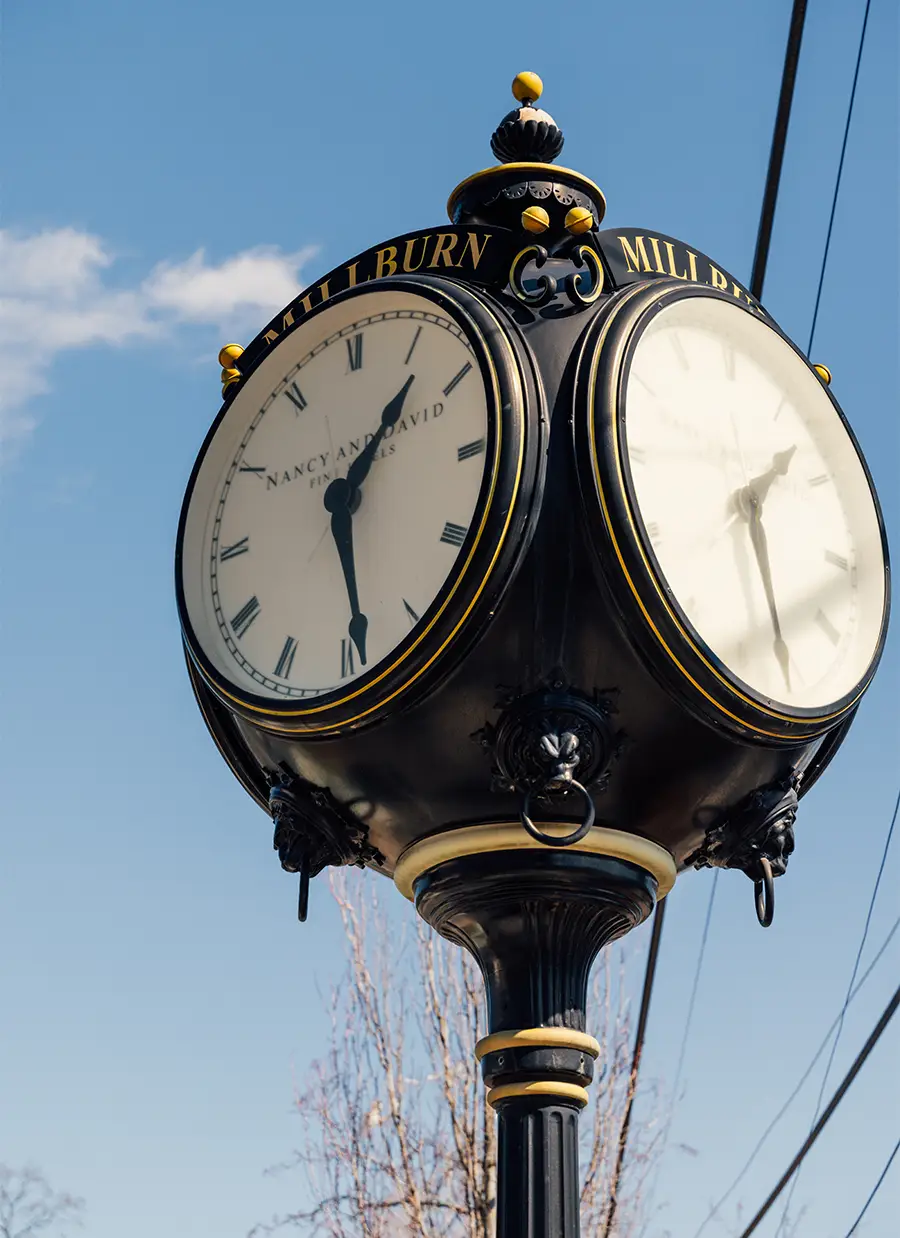 Ornate four-sided street clock on pole showing time against blue sky in town square