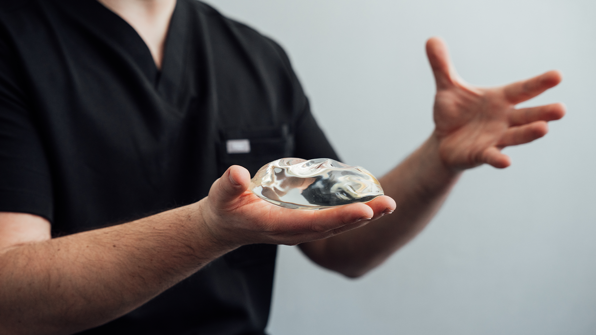 Person in black uniform holding white plate with food while gesturing with hand during presentation - Breast in Parsippany, NJ.