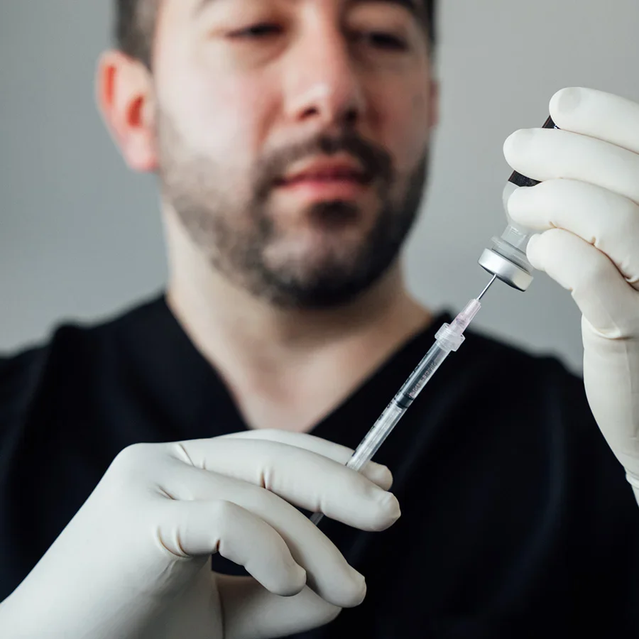 Healthcare professional preparing medical syringe for injection while wearing white protective gloves - Injectables in Parsippany, NJ.