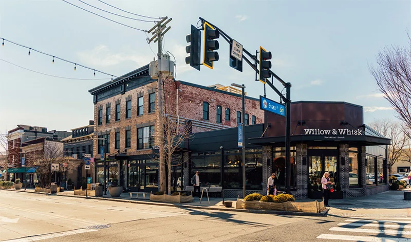 Historic downtown street corner with brick buildings, storefronts, and traffic light on sunny day