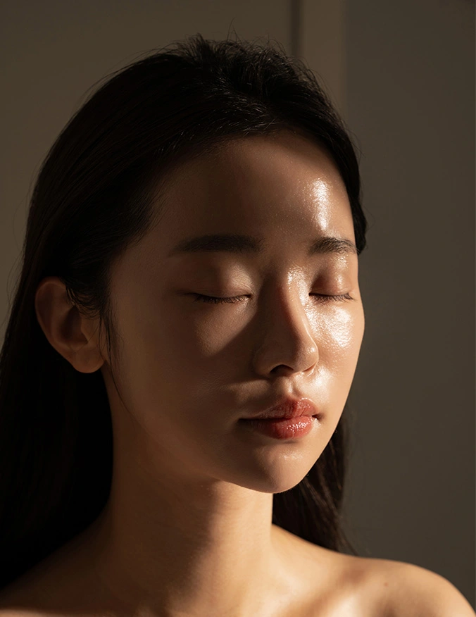 Woman with closed eyes in natural sunlight casting shadows across her peaceful face - microneedling in Parsippany, NJ.