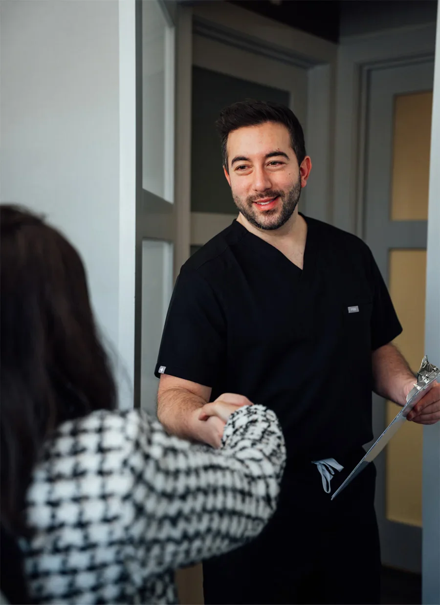 Doctor Shuja in scrubs consulting with patient in medical office setting