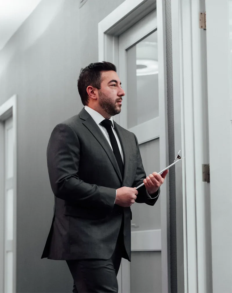 Dr Shuja in suit holding tablet standing in modern office hallway