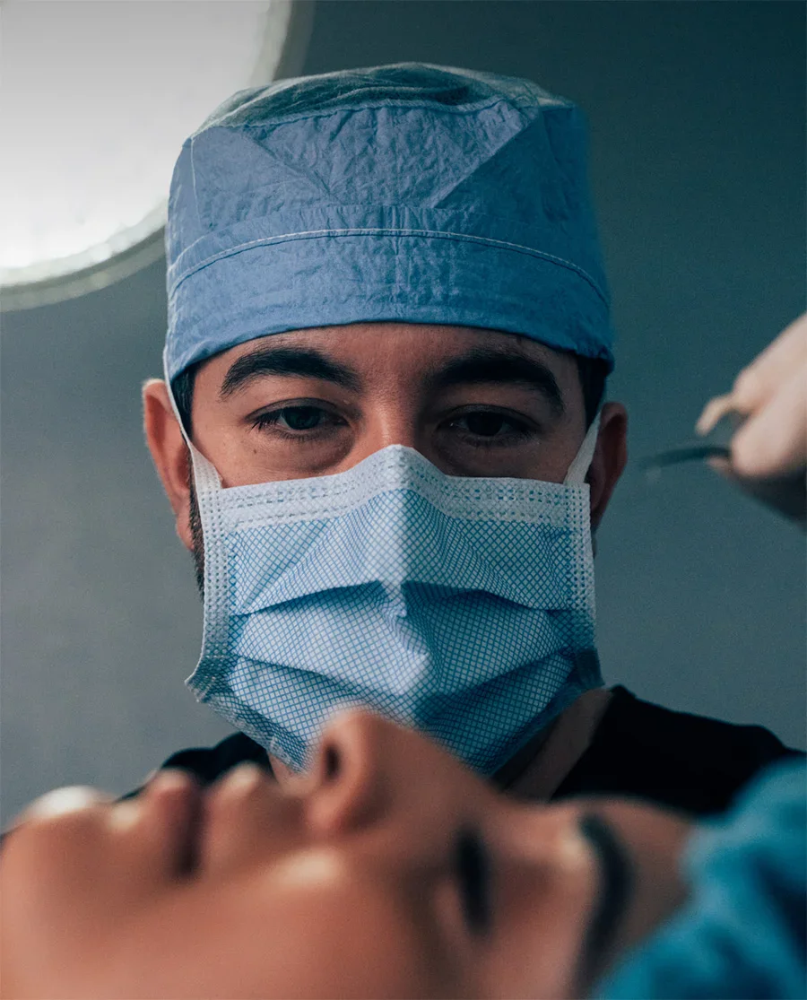 Surgeon wearing surgical mask and cap performing medical procedure in operating room - Reconstructive in Parsippany, NJ.